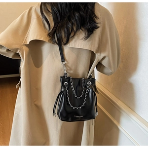 Detail of black leather bucket bag with silver chain handle and printed fashion text