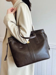 Deep brown large capacity faux leather tote bag with gold hardware worn by model