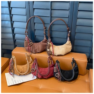 Variété de sacs hobo en daim avec détails de nœuds et charms sur un banc en cuir
