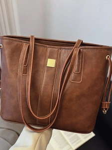Brown vintage leather tote bag with gold hardware in a warm lifestyle setting