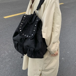 Detail of black suede backpack featuring silver stud rivets and symmetrical front pockets