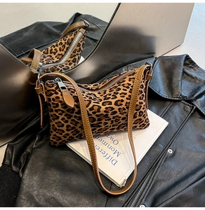 Leopard print underarm bag with zipper detail on a leather jacket and book background