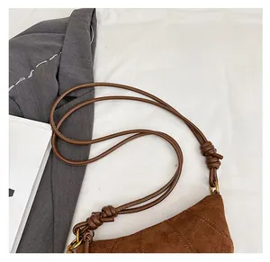 Detail of suede shoulder bag showing adjustable knotted strap and metal ring buckle