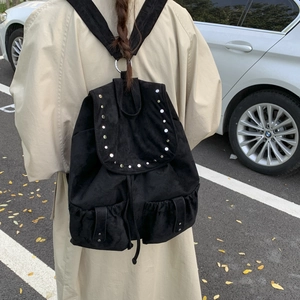 Detail view of black faux suede backpack with flap cover and metal stud rivet accents