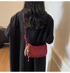 Dettaglio borsa a sella in pelle bordeaux opaca con nappa vintage di perline in legno