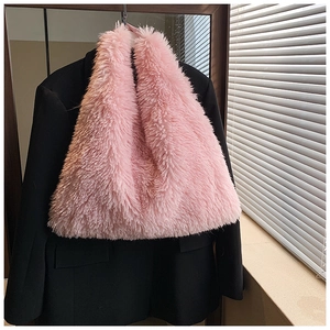 Detail shot of a soft pink faux fur tote bag hanging on a black blazer for texture contrast