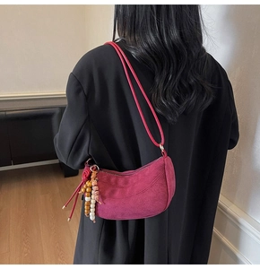 Dettaglio della borsa hobo in camoscio rosso rosa con ciondolo in legno su modella
