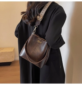 Detail of vintage dark brown bucket bag with ethnic woven wide strap and gold hardware