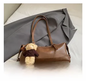 Close-up of a brown retro bowling shoulder bag with a cute plush bear charm detail