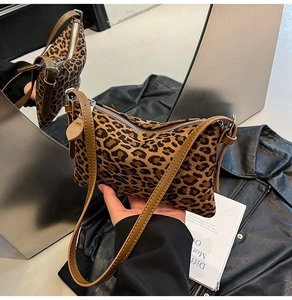 Detail of leopard print underarm bag featuring brown leather straps and silver metal zipper