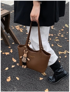 Détail du sac cabas en cuir marron avec lettrage doré et pendentif lapin mignon