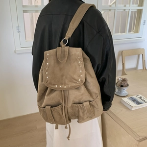 Detail of khaki suede backpack featuring silver metal rivets and buckle pockets for women