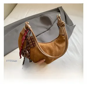Gros plan détaillé d'un sac demi-lune en daim marron foncé avec nœuds artistiques