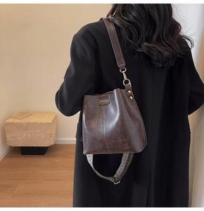 Detail of vintage brown bucket bag featuring woven strap and textured leather finish