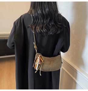 Dettaglio borsa a mezzaluna in camoscio marrone scuro con nappa di perline vintage sul cappotto