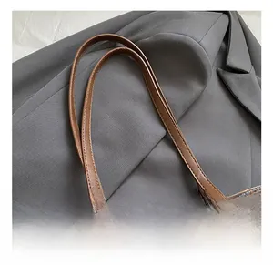 Detail of brown leather strap with silver buckle and metal zipper on a retro tote bag
