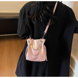 Detail of pink leather bucket bag with drawstring closure and metal chain shoulder strap
