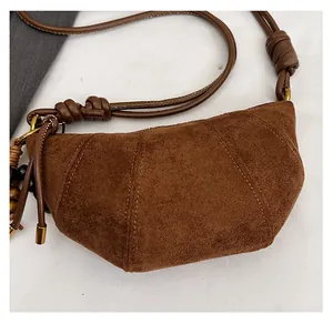 Detail view of brown suede croissant bag with knotted strap and wooden bead charm