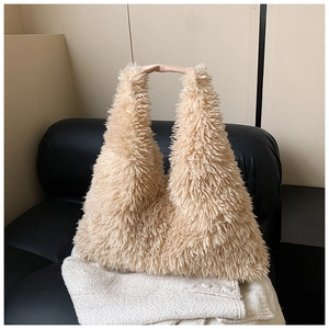 Close-up of a plush beige faux fur tote bag on a black leather sofa in a warm room