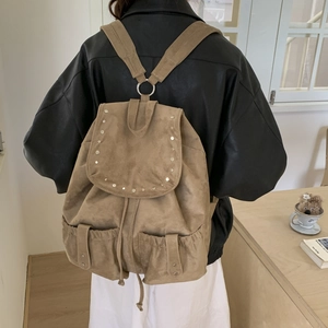 Detail of suede backpack with metal rivets and dual front buckle pockets for women