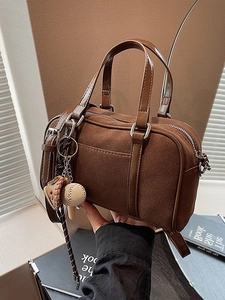 Dark brown suede Boston bag with smooth leather handles and baseball charm accessory