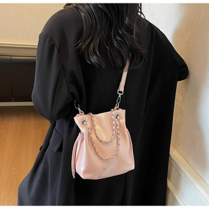 Detailed back view of model wearing pink leather bucket bag with silver chain strap