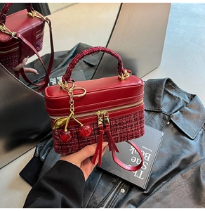 Detail of red tweed and leather handbag with cherry charm and tassel zippers