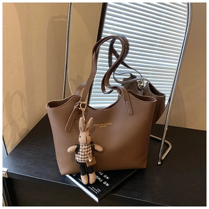 Détail d'un grand sac cabas en cuir marron avec logo doré et charm lapin suspendu