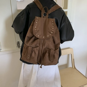 Close-up of brown suede backpack with rivet flap and double pockets for women