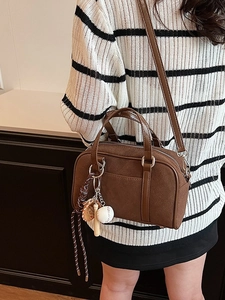 Brown Boston shoulder bag with vintage suede texture and sporty charms shown on model