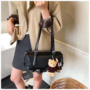 Detail of black glossy PU leather Boston bag featuring a cute brown teddy bear pendant