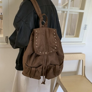 Detail of dark brown canvas backpack featuring vintage rivets and drawstring closure