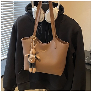 Détail d'un sac cabas marron en similicuir avec lettrage doré et pendentif lapin
