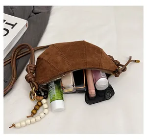 Detail showing deep brown suede croissant bag interior capacity for cosmetics and phone
