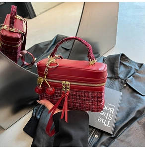 Detail of burgundy box bag showing tweed texture, gold zipper and cherry charm