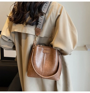 Detail of vintage brown bucket bag with lychee texture and geometric woven strap