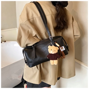 Black PU leather pillow bag with brown plush bear charm shown on model's shoulder