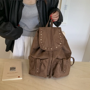 Detailed close-up of brown suede-textured backpack with stud accents and drawstring closure