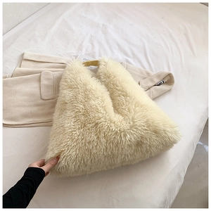 Close-up of fluffy faux fur texture and yellow handle on cream oversized shoulder bag