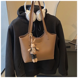 Détail du grand sac cabas en cuir marron avec un pendentif lapin et texte imprimé