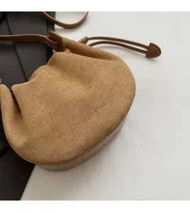 Détail du sac bandoulière demi-lune en daim marron vintage avec texte de mode embossé