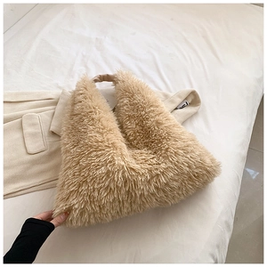 Detail of soft fuzzy plush tote bag with contrasting dark brown handle on a bed