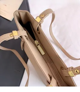 Detail of the golden alloy zipper and lychee textured leather on this beige tote bag