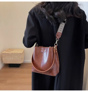 Detail of vintage brown bucket bag with textured leather and jacquard woven strap