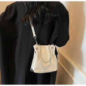 Detail of a minimalist cream white leather bucket bag with silver chain and shoulder strap