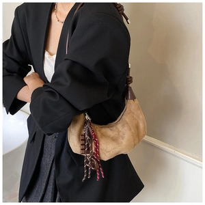 Détail du sac croissant en daim marron avec pendentif chocolat et bandoulière tressée