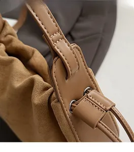 Vue détaillée des coutures décoratives sur un sac seau en daim marron avec anneau métal