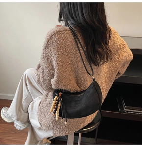 Dettaglio borsa hobo in camoscio nero con nappa in perline di legno e finiture dorate