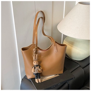 Détail d'un sac cabas marron avec un pendentif lapin en peluche et imprimé texte doré