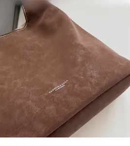 Gros plan du sac cabas en cuir marron vintage montrant la texture et le logo de la mode